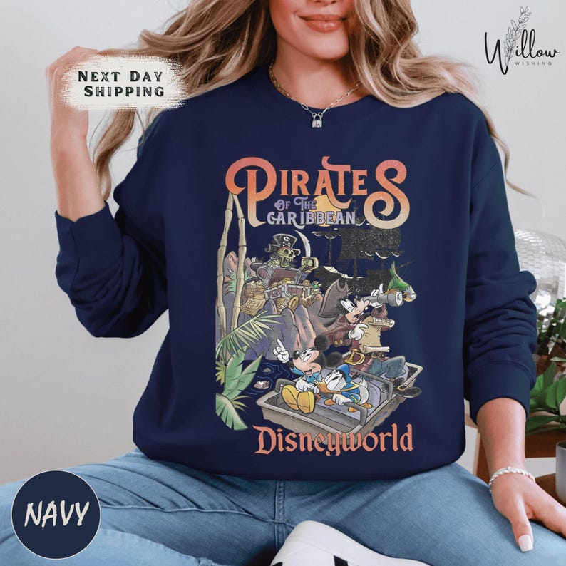 A woman wearing a navy blue sweatshirt with a graphic of Disney characters from the Pirates of the Caribbean franchise.