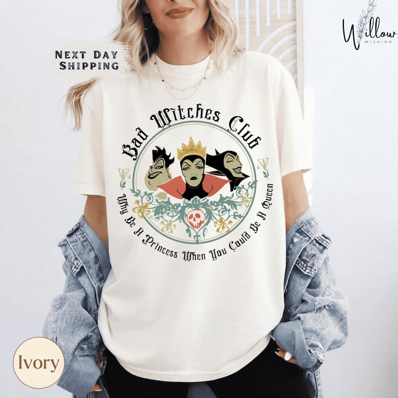 A woman wearing a white t-shirt with a graphic design featuring three cartoonish female characters and text.