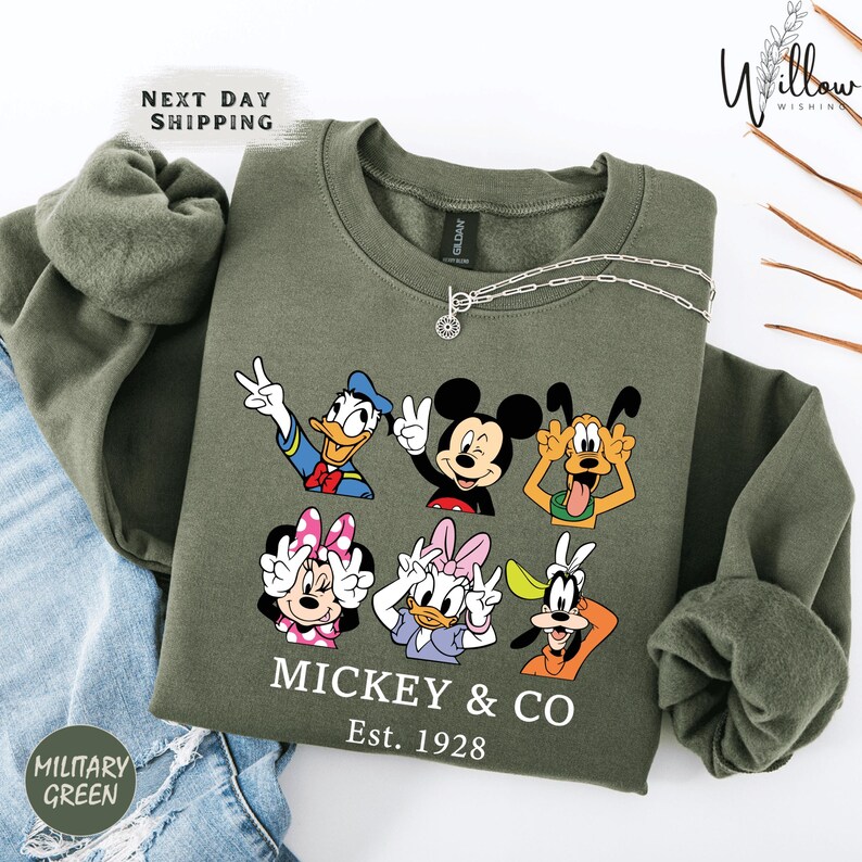 A green sweatshirt with a graphic of Disney characters Mickey Mouse and Donald Duck, along with the text "MICKEY & CO Est. 1928".