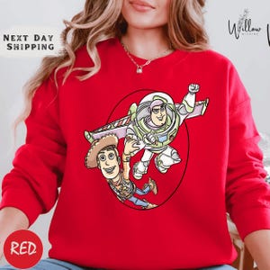 A red sweater with a cartoon image of a character from the Toy Story franchise, specifically Woody and Buzz Lightyear, printed on it.