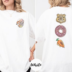 A woman wearing a white t-shirt with a cartoon character and a police badge on the back.