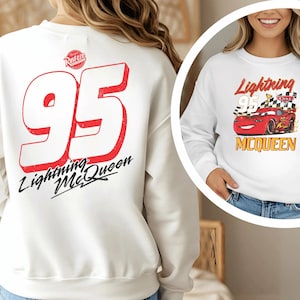 a woman wearing a white sweatshirt with a red and black design on the back.