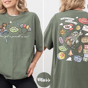 A woman wearing a green t-shirt with various cartoon characters and text printed on it.