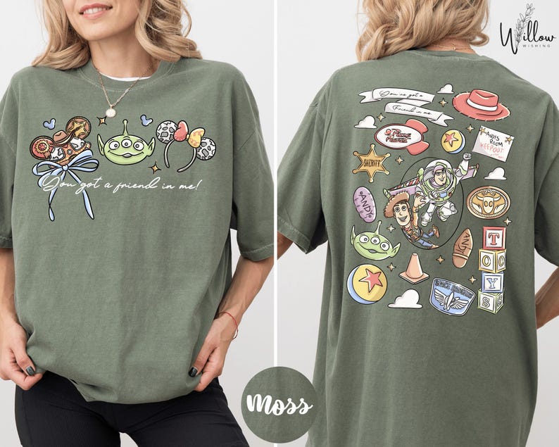 A woman wearing a green t-shirt with various cartoon characters and text printed on it.