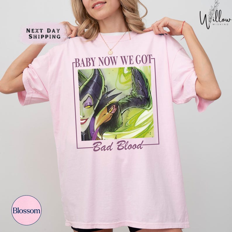 A woman wearing a pink t-shirt with a graphic design featuring a character from the Disney movie "Bad Blood".