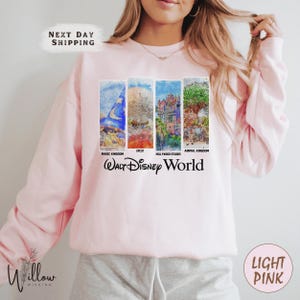 A woman wearing a pink sweatshirt with a collage of Disney World images on it.