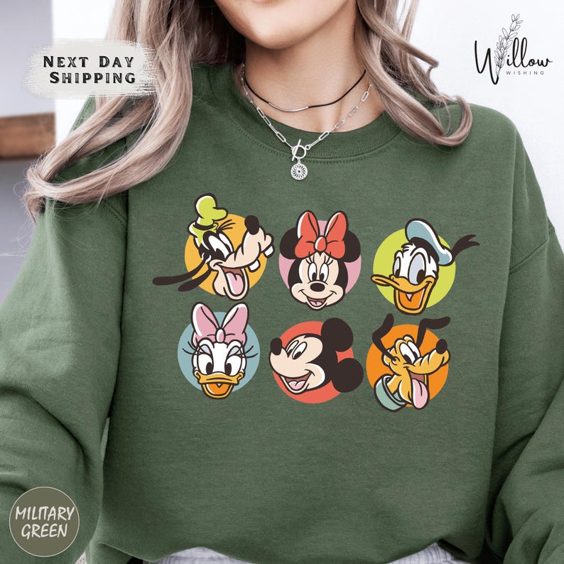 A person wearing a green sweatshirt with a graphic of Disney character faces arranged in a grid pattern.