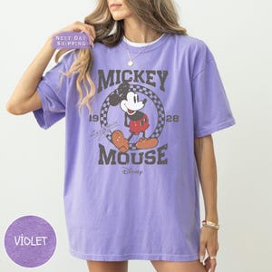 a woman wearing a purple mickey mouse t - shirt