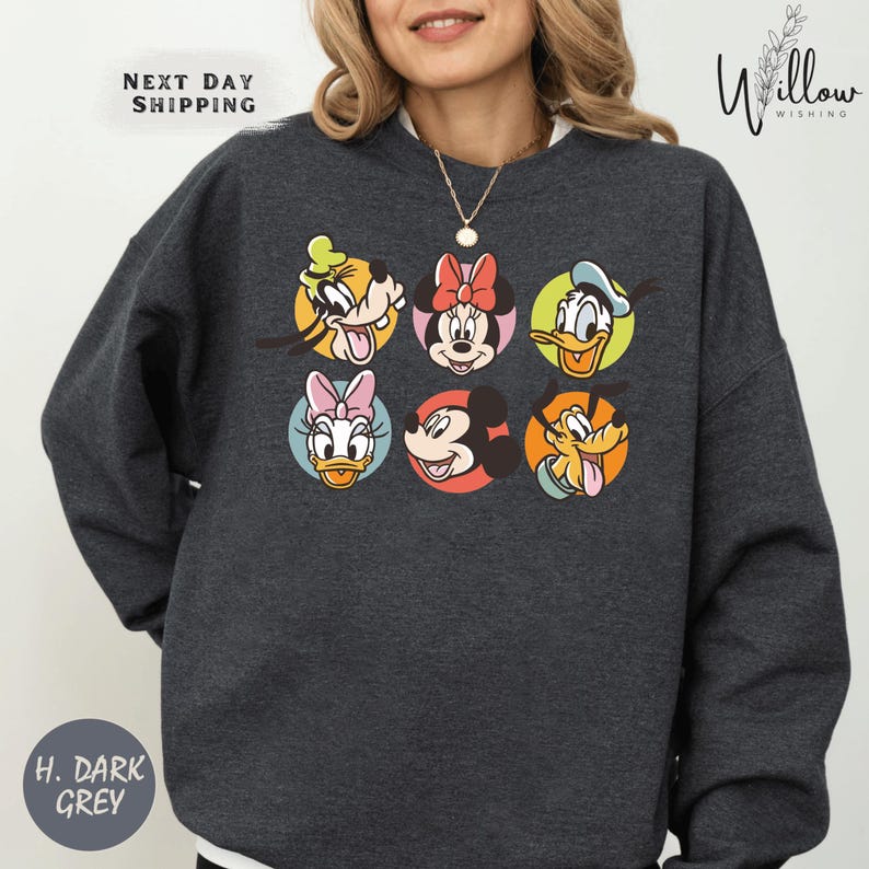 A woman wearing a gray sweatshirt with a graphic of Disney characters on it.