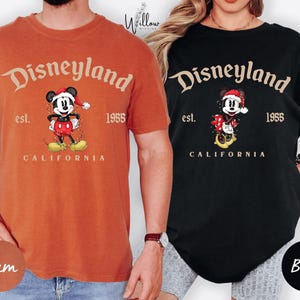 two people wearing t-shirts with the Disney theme park logo and text.