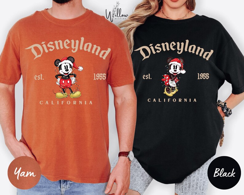 two people wearing t-shirts with the Disney theme park logo and text.