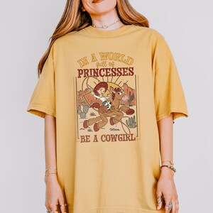 a woman wearing a yellow shirt that says, is a proud princesses be a