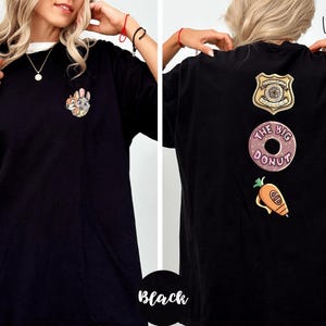 A woman wearing a black t-shirt with various cartoon and police-themed designs on the back.