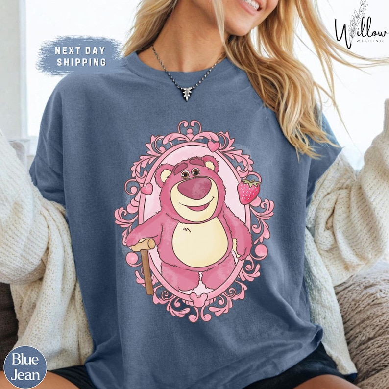 a woman wearing a blue shirt with a pink bear on it
