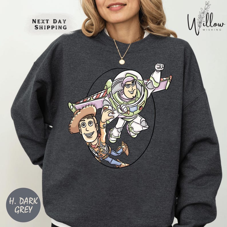 A woman wearing a gray sweatshirt with a graphic of two characters from the Toy Story franchise, Buzz Lightyear and Woody, printed on the front.