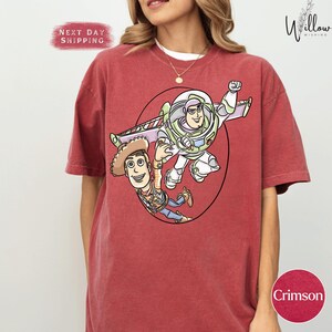 A red t-shirt with a cartoon character design featuring a boy and a girl.