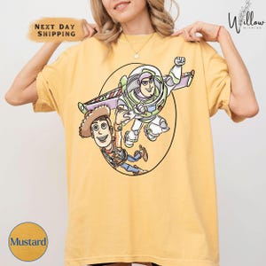 A woman is wearing a yellow t-shirt with a cartoon image of Buzz Lightyear and Woody from Toy Story.