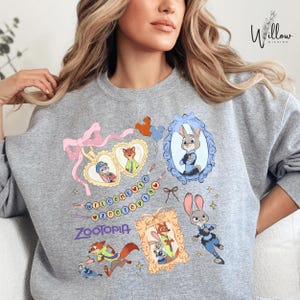 A woman wearing a gray sweatshirt with a colorful graphic design featuring cartoon animal characters and text.