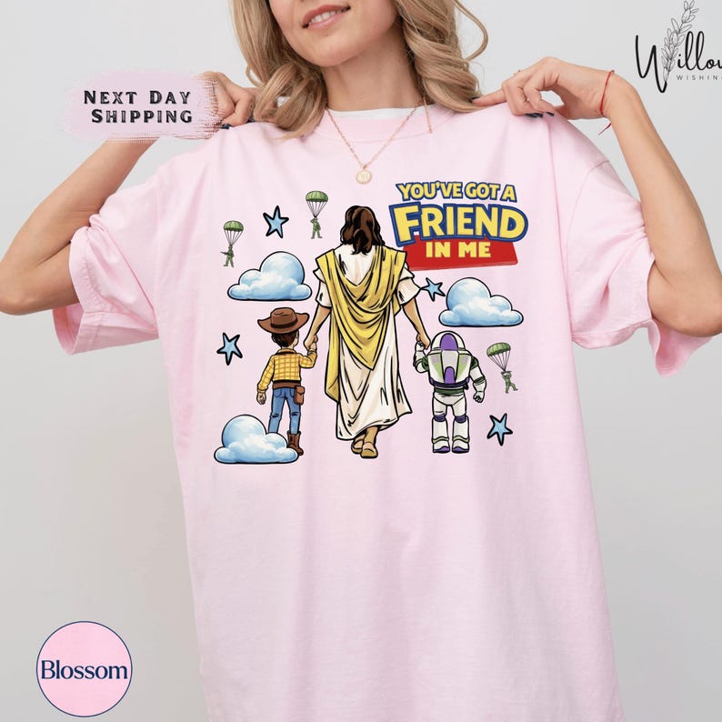 A woman wearing a pink t-shirt with a graphic design depicting a cartoon character, likely from the Toy Story franchise, holding hands with two other characters.