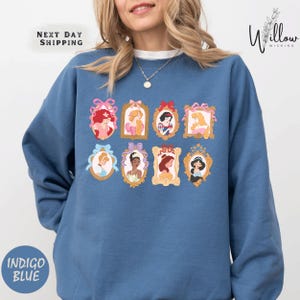 A woman wearing a blue sweatshirt with a graphic design of various Disney princesses.