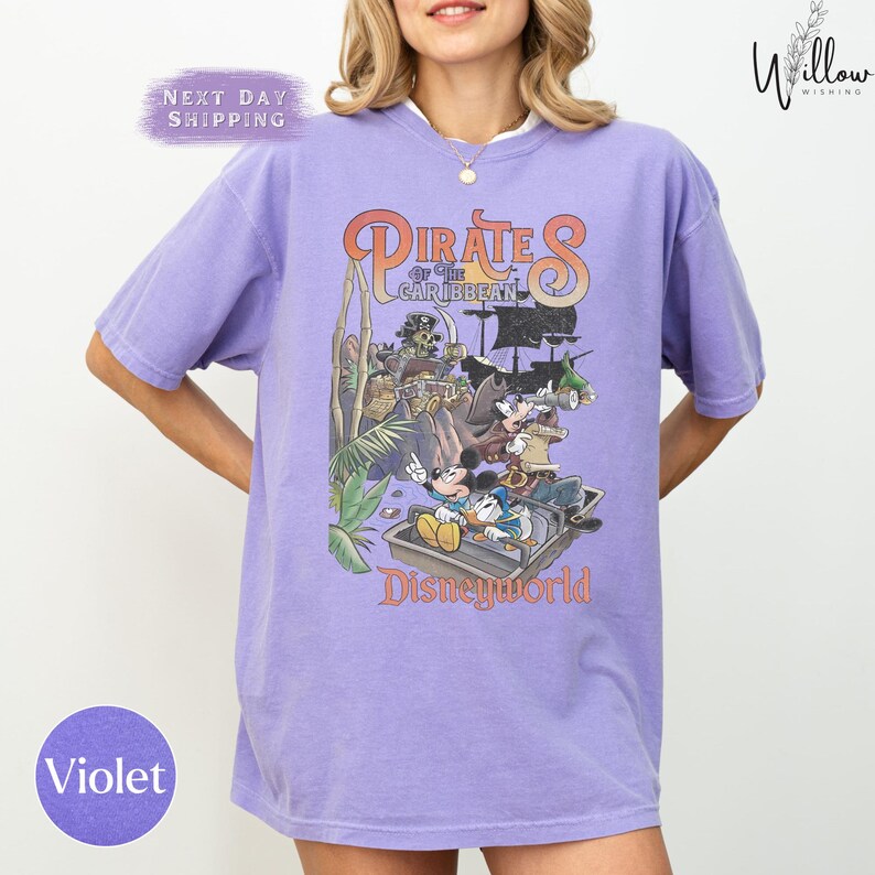A woman wearing a purple t-shirt with a graphic design of Disney characters from the Pirates of the Caribbean ride at Disneyworld.