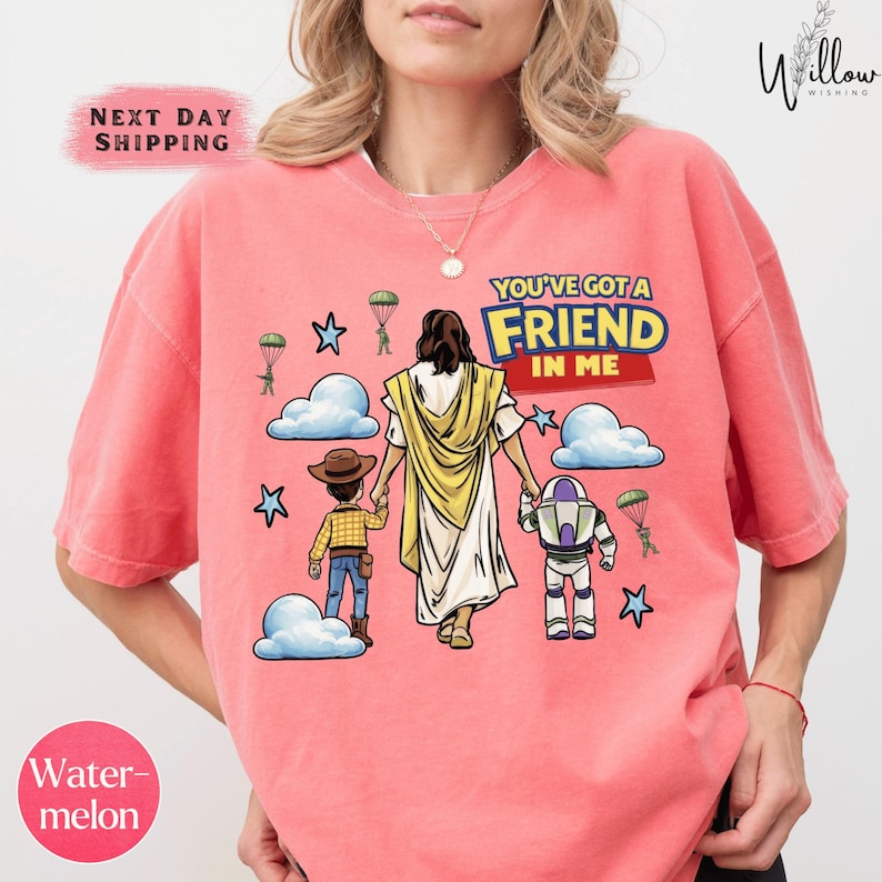 A woman wearing a pink t-shirt with a graphic design depicting a cartoon-style illustration of Jesus Christ, a boy, and a robot.