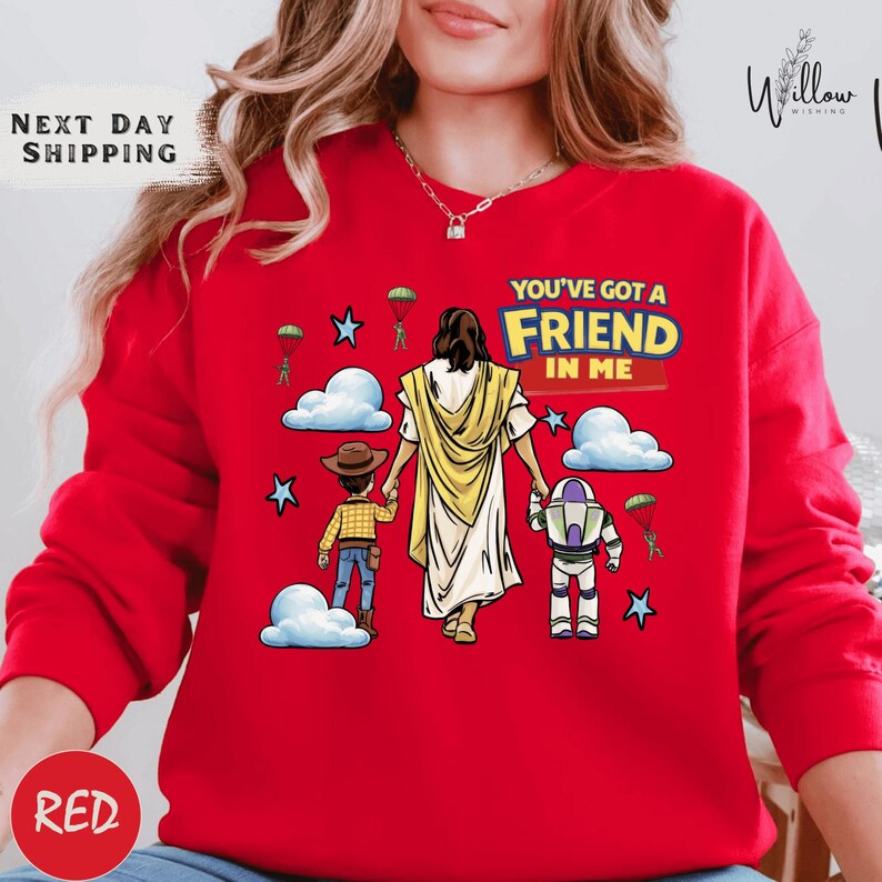 A red sweater with a cartoon illustration of a person holding a robot and a child, along with the text "You've got a Friend in Me" and a Bible verse reference.