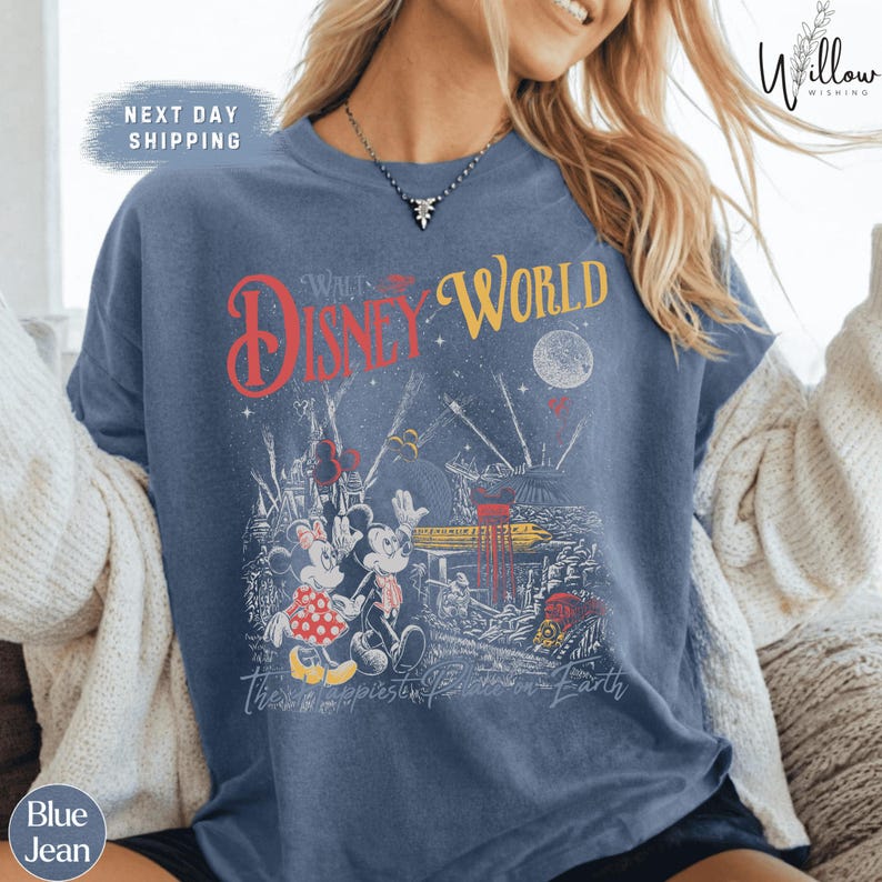 A woman wearing a blue t-shirt with a Disney World-themed graphic printed on it.