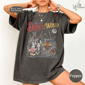 A person wearing a gray t-shirt with a graphic design featuring Disney characters and the text "Walt Disney World".