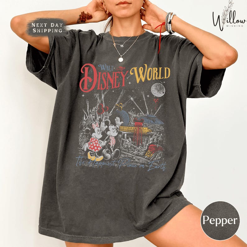 A person wearing a gray t-shirt with a graphic design featuring Disney characters and the text "Walt Disney World".