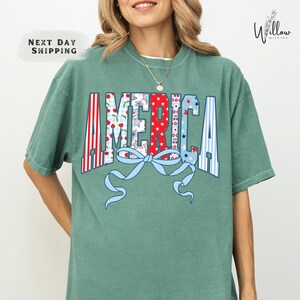 A woman wearing a green t-shirt with the word "AMERICA" printed on it.