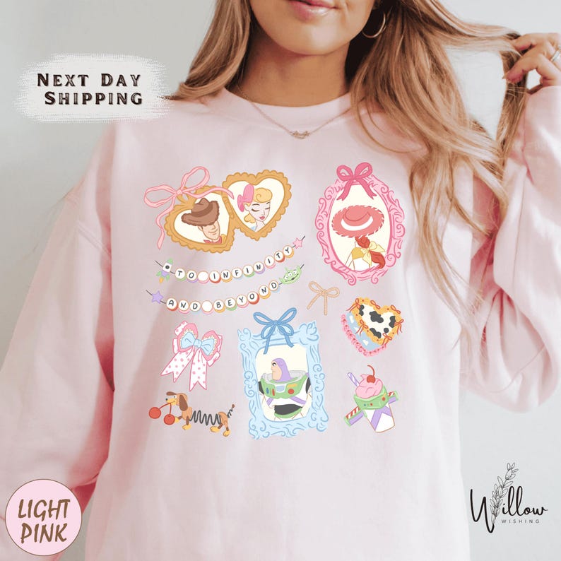 A woman wearing a pink sweatshirt with various cartoon-style illustrations and text on it.