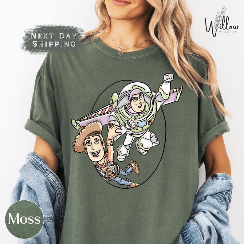 A woman wearing a green t-shirt with a graphic of Buzz Lightyear and Woody from Toy Story.