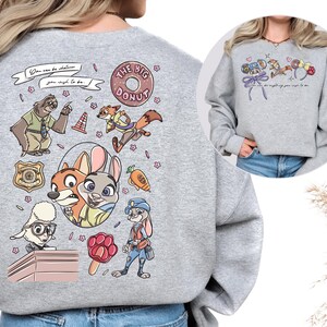 a grey sweatshirt with a colorful and whimsical design of cartoon animal characters, including a dog, cat, and rabbit, along with various other elements such as flowers, balloons, and a police officer.