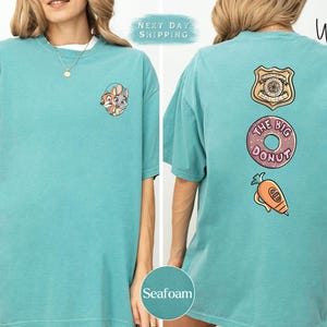 The image is a collage of two photos of a woman wearing a turquoise t-shirt with various cartoon-style designs and text on the back.