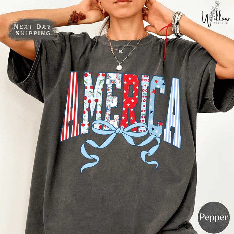 A person wearing a gray t-shirt with the word "AMERICA" printed on it, along with a bow and other patriotic symbols.