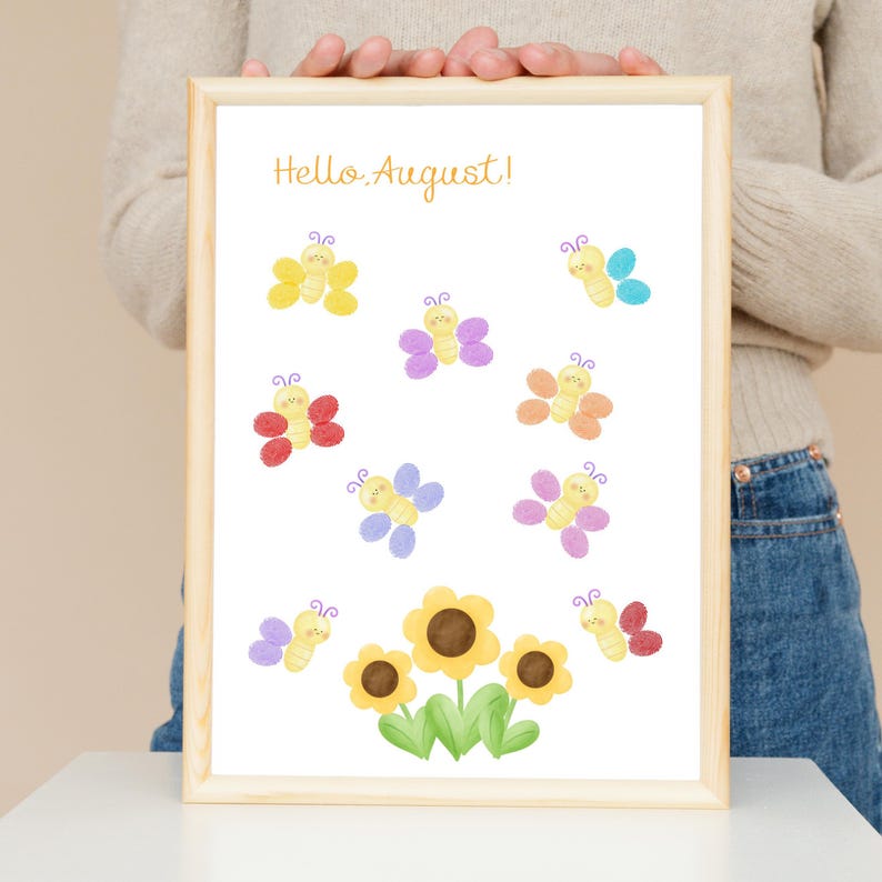 Puede incluir: Una l&aacute;mina enmarcada con el texto Hello August en letra cursiva naranja en la parte superior. Debajo del texto hay ocho peque&ntilde;as mariposas coloridas con caras sonrientes, dispuestas alrededor de tres girasoles amarillos con centros marrones y hojas verdes.