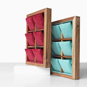 May include: Two wooden jewelry organizers with six compartments each. One organizer has red velvet inserts, the other has teal velvet inserts. The wooden frames have a natural wood grain finish. The organizers are displayed on a white surface.