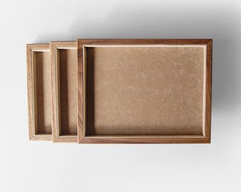 Puede incluir: Tres marcos de fotos rectangulares de madera con acabado de madera natural están dispuestos sobre una superficie blanca. Los marcos tienen un diseño simple y clásico con un respaldo marrón. Los marcos están vacíos, listos para fotos o obras de arte.