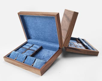 May include: A wooden watch box with a dark brown finish and a blue velvet interior. The box features multiple compartments with individual blue velvet cushions for watches, and a hinged lid that opens to reveal the organised storage space inside.