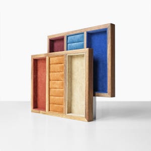 May include: Wooden jewellery display trays with velvet inserts in various colours. The rectangular trays have a natural wood finish and compartments in red, orange, beige, blue, and teal. Designed to hold rings, necklaces, and other jewellery items.