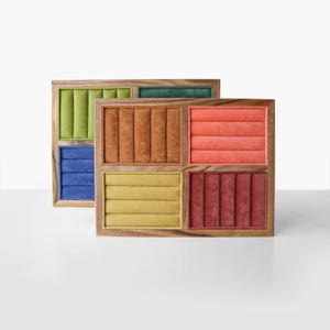 May include: Two rectangular wooden jewelry display trays featuring multiple velvet-lined slots. The trays contain sections in various colors including lime green, dark blue, forest green, brown, coral, mustard yellow, and deep red.