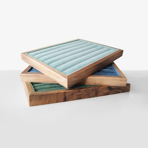 May include: Three wooden ring display trays with velvet lining. The top tray is light blue, the middle tray is dark blue, and the bottom tray is green.