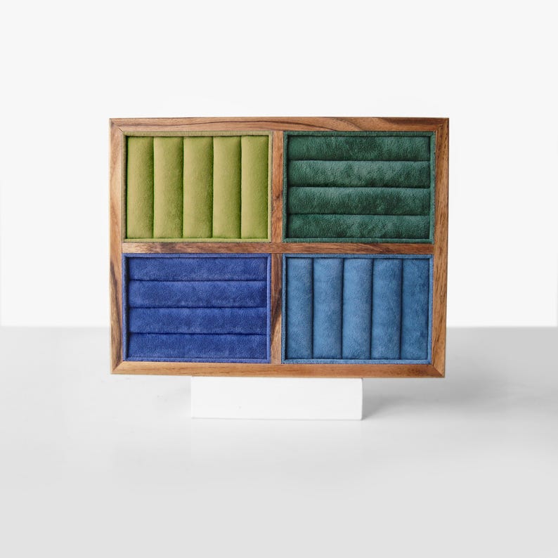 May include: A rectangular wooden jewelry display stand featuring four distinct quadrants lined with velvet fabric. The top left section is light green, the top right is dark green, the bottom left is royal blue, and the bottom right is sky blue.
