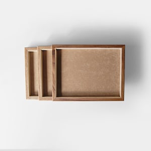 May include: Three wooden picture frames of different sizes, nested inside each other. The frames are made of dark wood with a natural finish.