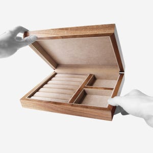 May include: A wooden jewelry box with a light brown finish and a beige velvet interior. The box has multiple compartments for storing rings, earrings, and other small items.