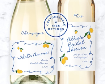May include: Two white wine bottles with blue and yellow labels. The champagne bottle label says "That's Amore!" with the text "Sam's Bridal Shower 6.8.24". The wine bottle label says "Allie's Bridal Shower" with the text "She found her main squeeze! 6.8.24".