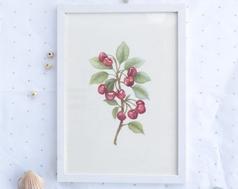 Könnte beinhalten: Ein gerahmtes Aquarellgemälde eines Kirschzweigs mit reifen roten Kirschen und grünen Blättern. Das Kunstwerk wird in einem weißen Rahmen vor einem weißen Hintergrund mit kleinen goldenen Punkten präsentiert. Dekorative Elemente sind Holzperlen und Muscheln.