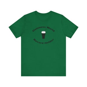 May include: A green t-shirt with a black graphic of a pint of Guinness and the text "Guinness World Record Holder".