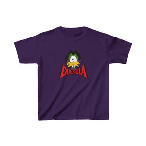 Puede incluir: Camiseta morada para jóvenes con un pato de dibujos animados con pajarita y el texto "Count Duckula" en rojo.